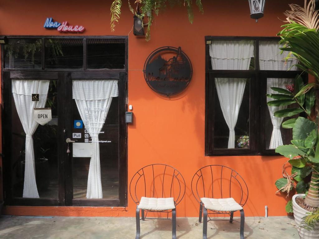 曼谷Non House Hostel บ้านนอนโฮสเทล的两把椅子,在一座橙色墙壁的建筑前