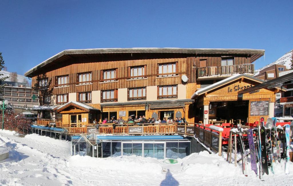 莱德萨阿尔卑斯夏尔巴酒店的雪地里的人在滑雪小屋外面