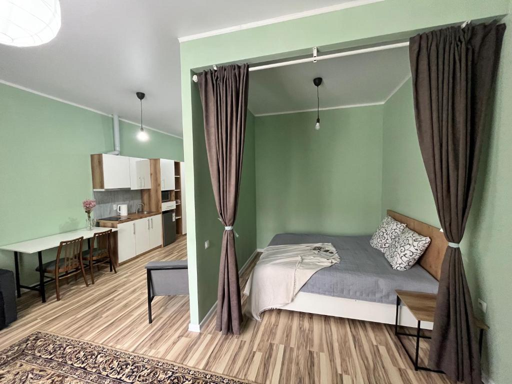 奥什SN Apartments的一间卧室设有绿色的墙壁、一张床和一张桌子