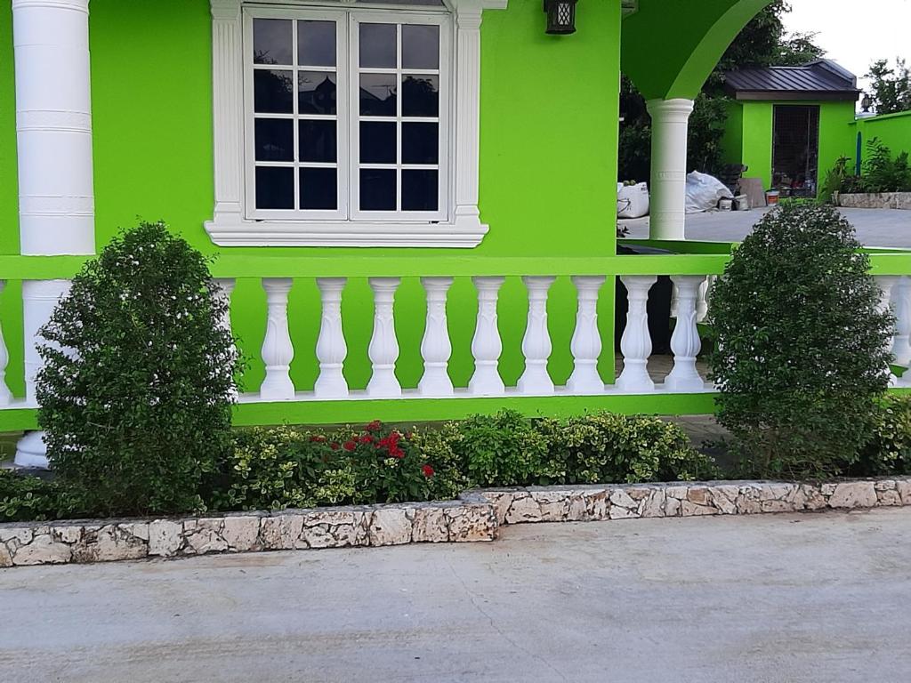 Bon AccordPESHERES INN & SPA的绿色的房子,设有窗户和白色的围栏