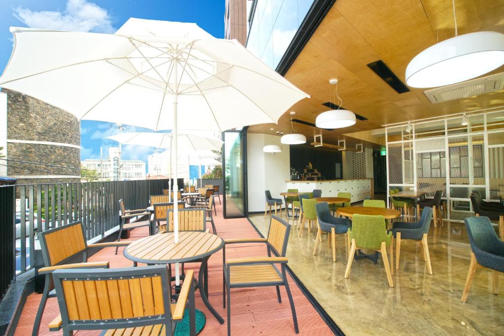 济州市I-Jin Hotel的一间带桌椅和遮阳伞的餐厅
