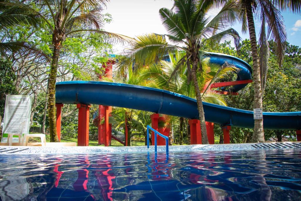 圣赫罗尼莫Hotel Lagotours的棕榈树游泳池中的蓝色水滑梯