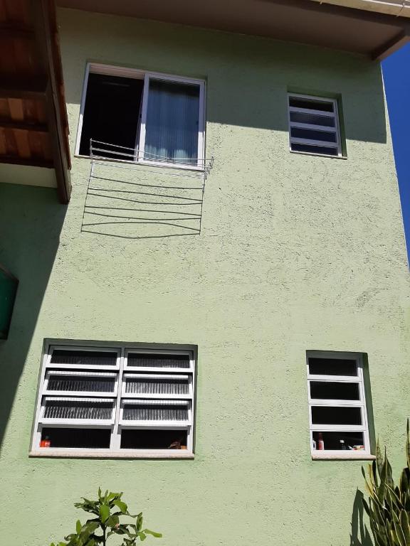 弗洛里亚诺波利斯Apartamento Atobá的两扇窗户位于绿色建筑的一侧