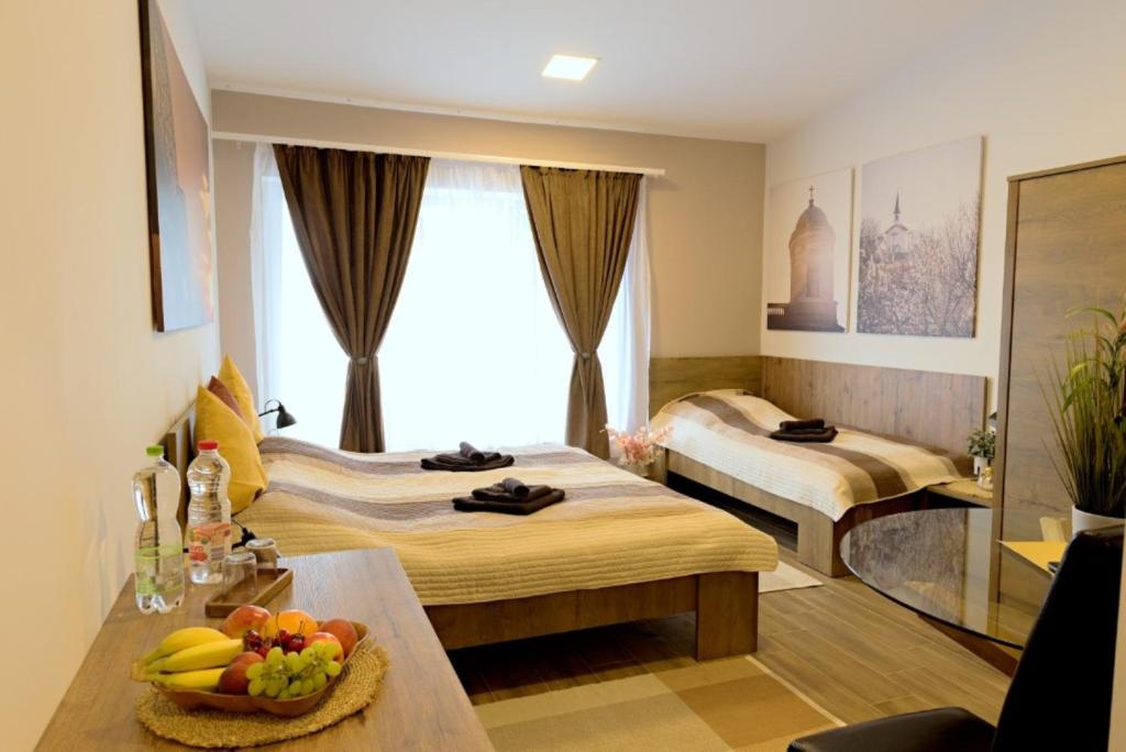 艾斯特根eHotel Esztergom的酒店客房设有两张床和一张带一碗水果的桌子。