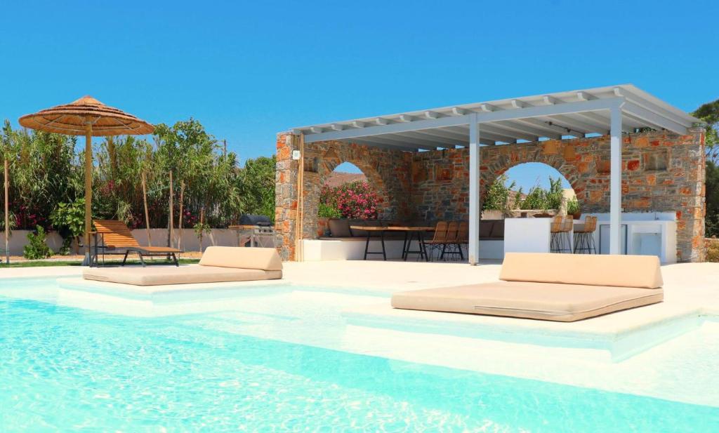 纳克索斯岛卡斯特拉基The Nine Graces - Kastraki Villas with Private Swimming Pool的一个带两张床和遮阳伞的游泳池