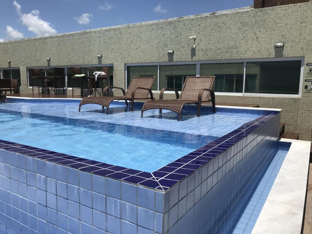卡贝德卢Flat Beira Mar de Intermares的一座带椅子的游泳池位于一座建筑的顶部