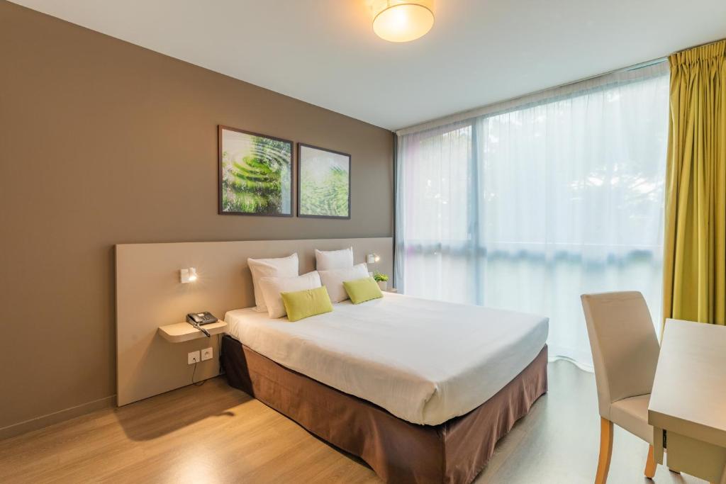 瑟松塞维涅雷恩-瑟松塞维涅城市公寓酒店的一间卧室设有一张大床和一个窗户。