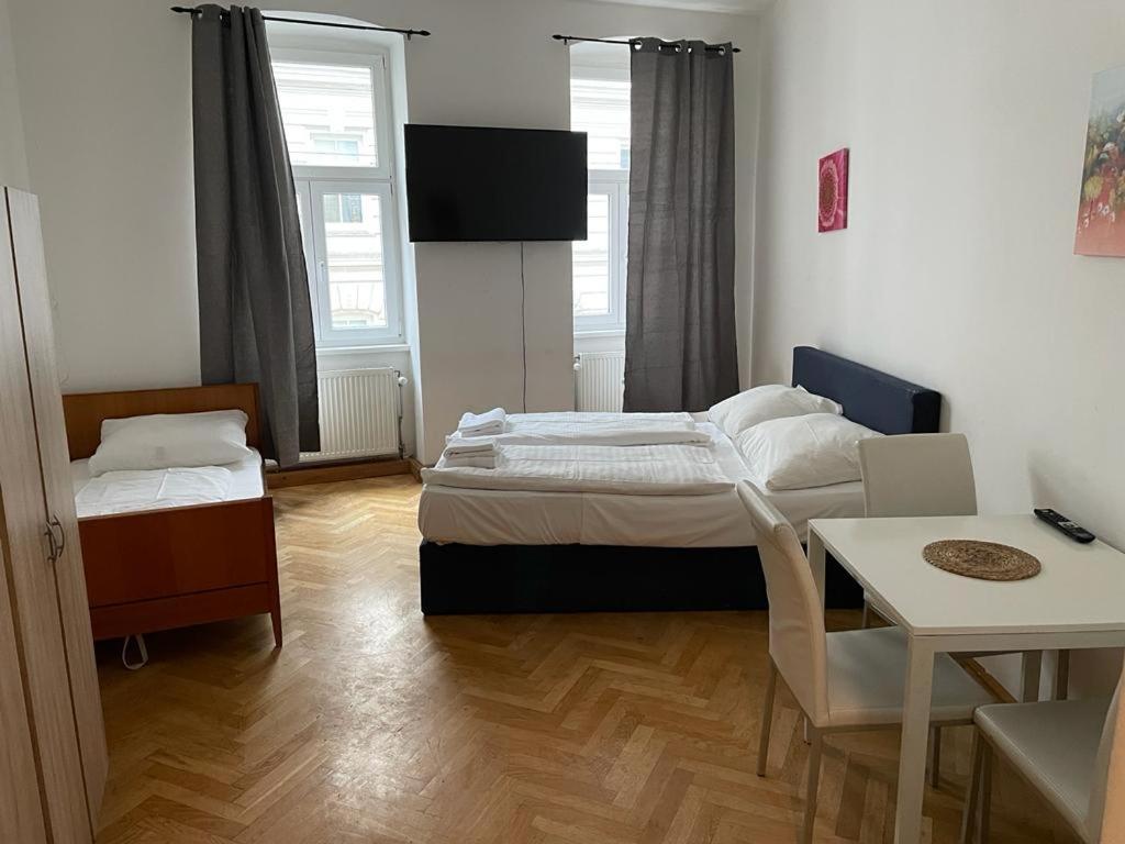 维也纳easybook-in的小房间设有两张床、一张桌子和一张桌子。