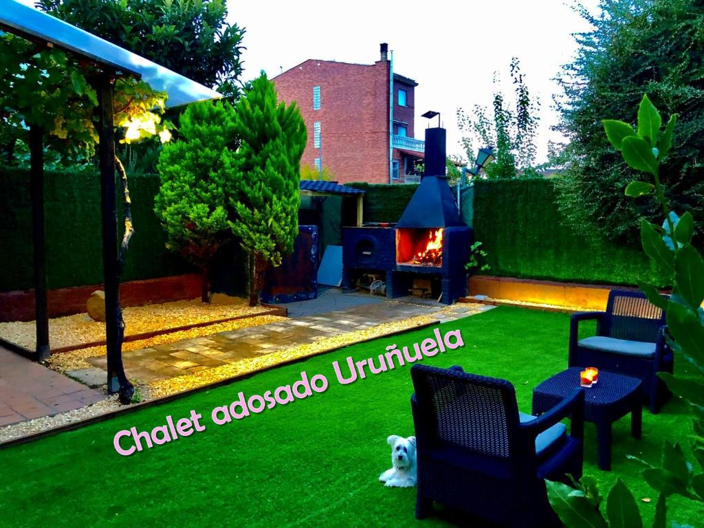 UruñuelaCHALET ADOSADO CON GARAGE Y TERRENO的后院设有草坪、壁炉和狗