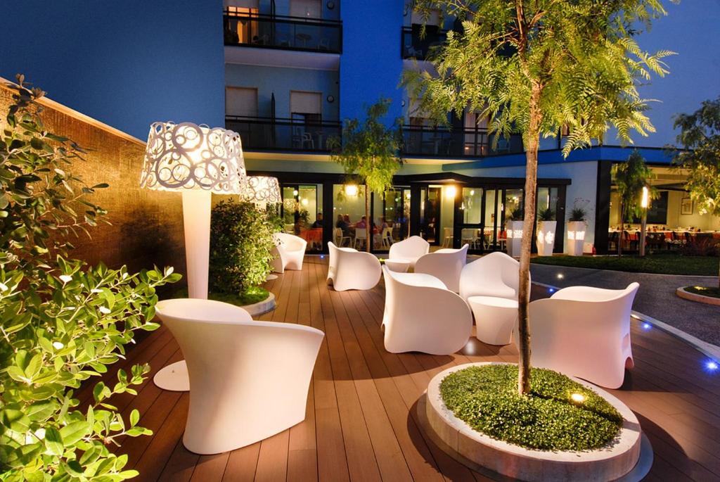 托尔托雷托大陆酒店的一座带白色椅子和一棵树的庭院和一座建筑