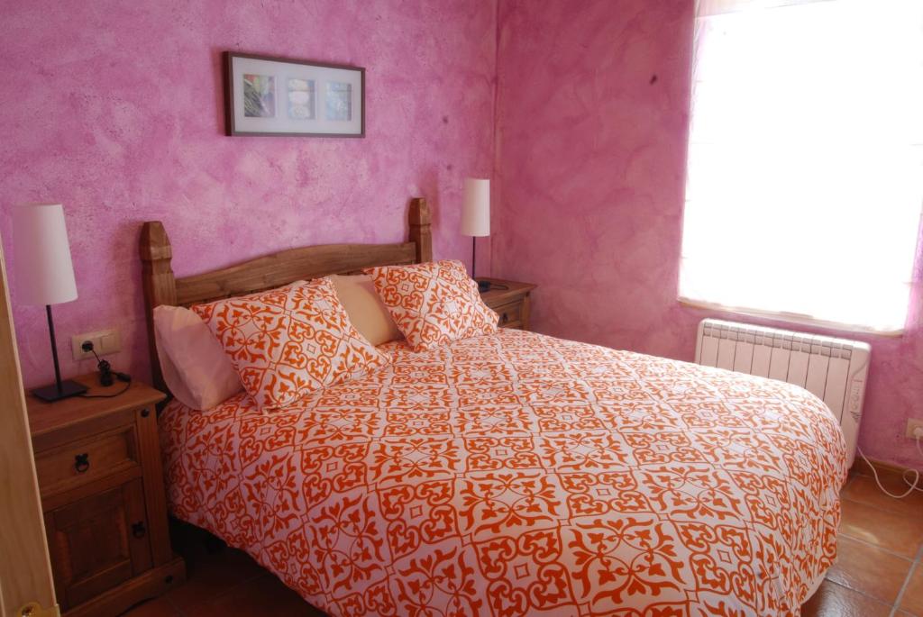 Soto y AmíoLa formigana的一间卧室配有一张床和粉红色的墙壁
