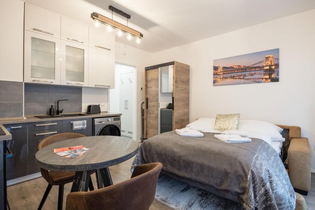 布达佩斯Central Sphere Apartment的一间卧室配有一张床铺和一张桌子,还设有一间厨房