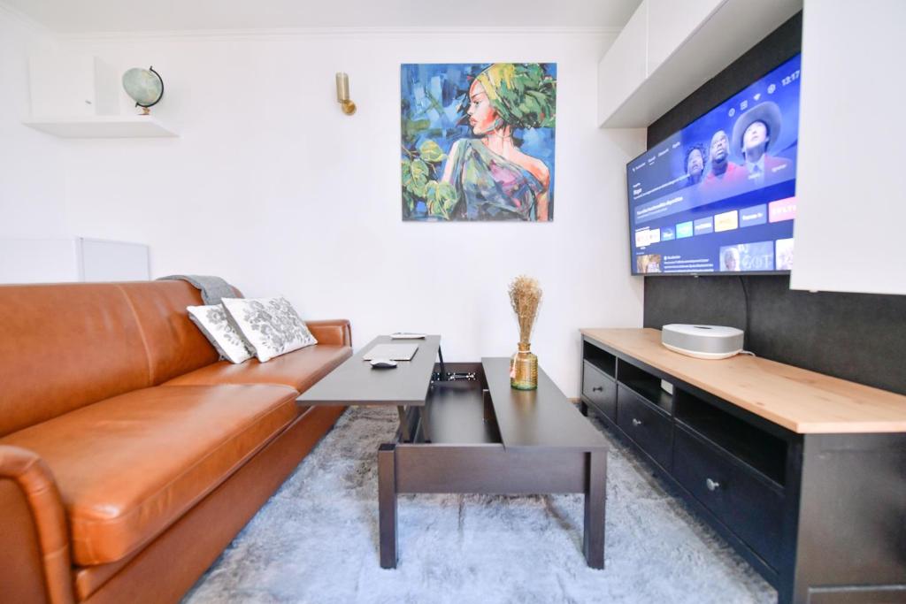巴黎Paris La Villette - Charming Apartment 2 rooms的客厅配有棕色真皮沙发和电视