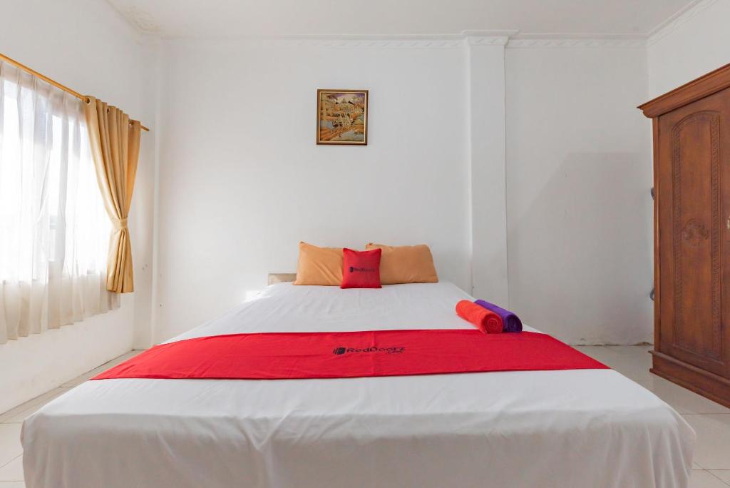 沙马林达RedDoorz near Samarinda Square的一间卧室配有一张带红色毯子的大床