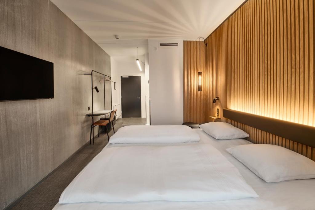 瓦埃勒Zleep Hotel Vejle的客房设有三张床和一台平面电视。