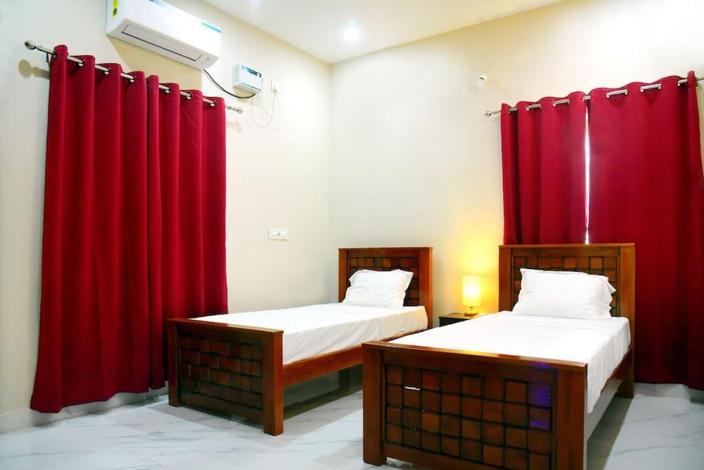 蓬蒂切里Sri Apartment 2BHK For Familys Couples Parking A1的配有红色窗帘的客房内的两张床