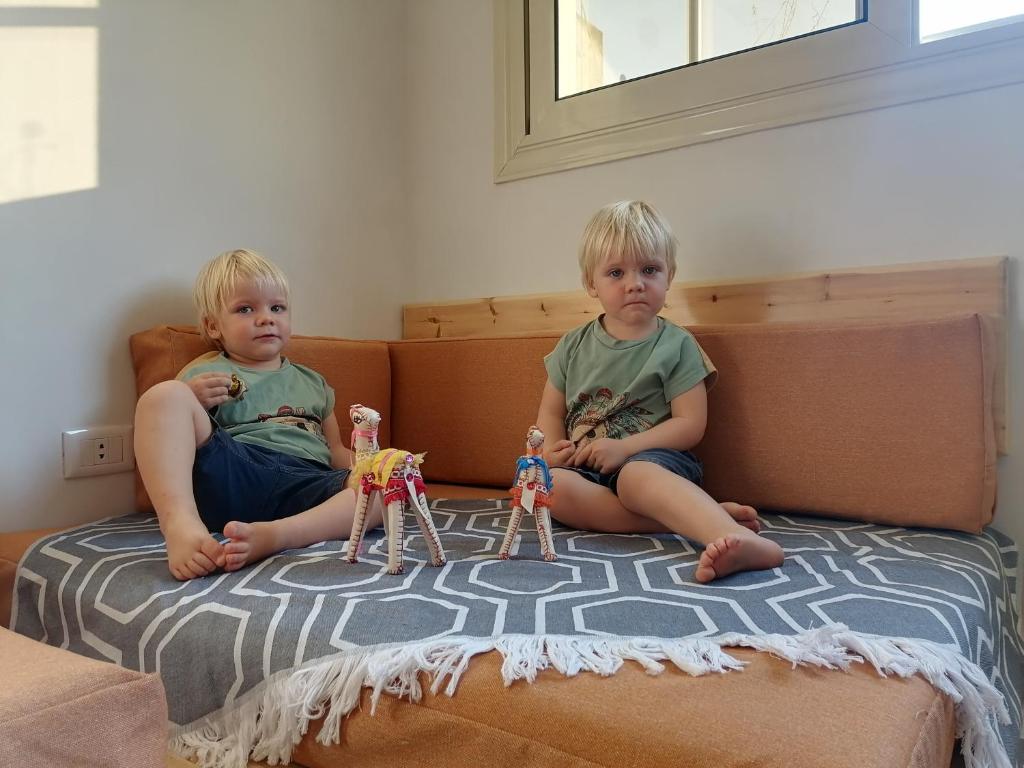 开罗Champollion Hostel的两个男孩坐在床上,床上有玩具娃娃