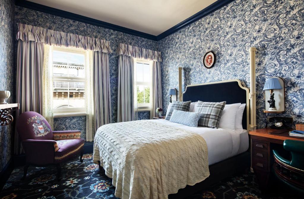 牛津The Randolph Hotel, by Graduate Hotels的卧室拥有蓝色的墙壁,配有一张床和椅子