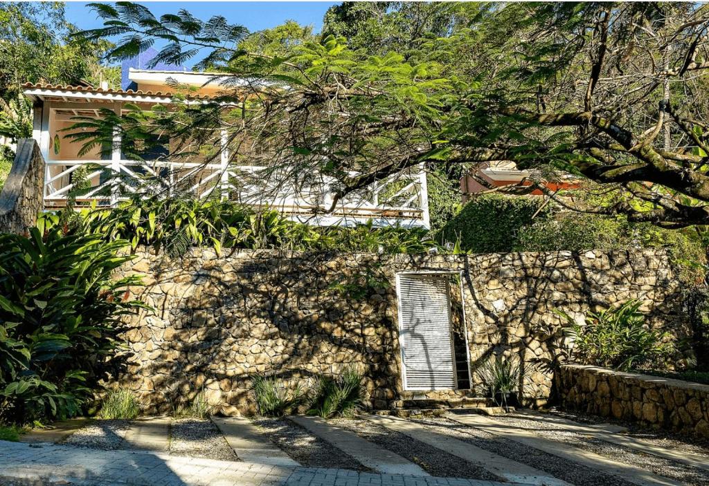 伊利亚贝拉Casas com jacuzzi e churrasqueira a 500 metros da Praia do Perequê na Ilhabela的一座有窗户的建筑,前面有一棵树