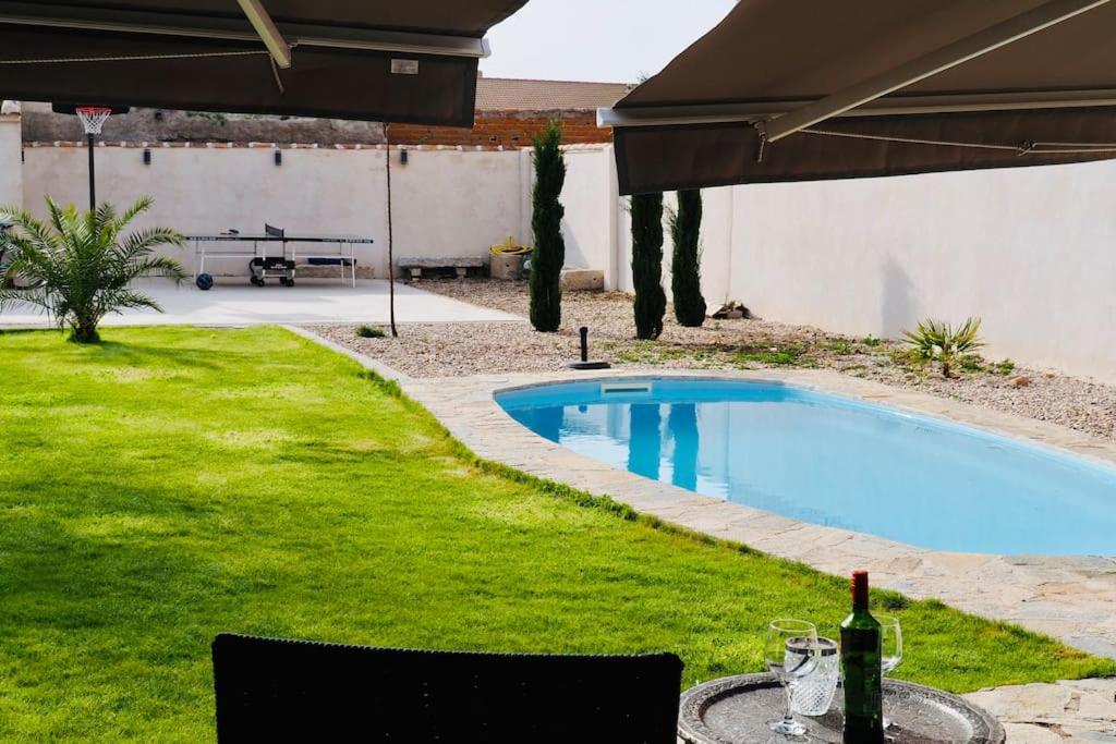 TotanésVilla Mandrés. Casa con jardín y piscina. Proximo a Puy Du Fou.的后院设有游泳池和带一瓶葡萄酒的桌子