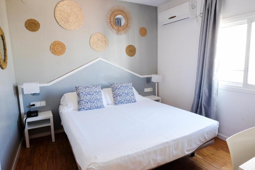 锡切斯苏布尔酒店的一间卧室配有白色床和蓝色枕头