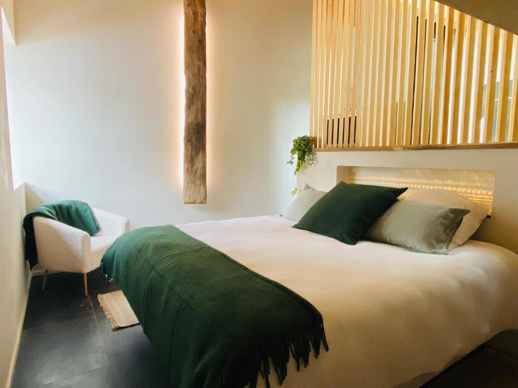 普雷芒翁La Loge de la Dolarde - Chambre Sud的一间卧室配有一张带绿色床单的大床和椅子