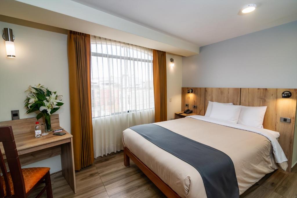 阿雷基帕Casa Villa Arequipa的配有一张床、一张书桌和一扇窗户的酒店客房