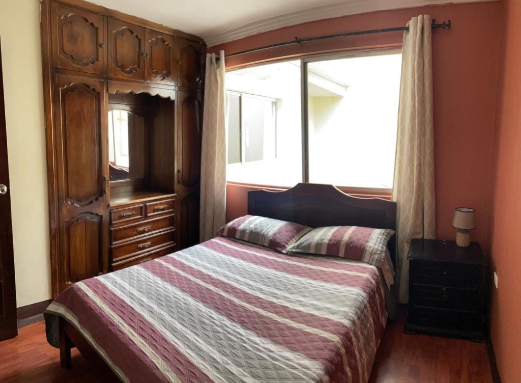 昆卡ALOJAMIENTOS HOSTAL REST HOUSE的一间卧室配有一张床、一个梳妆台和一扇窗户。