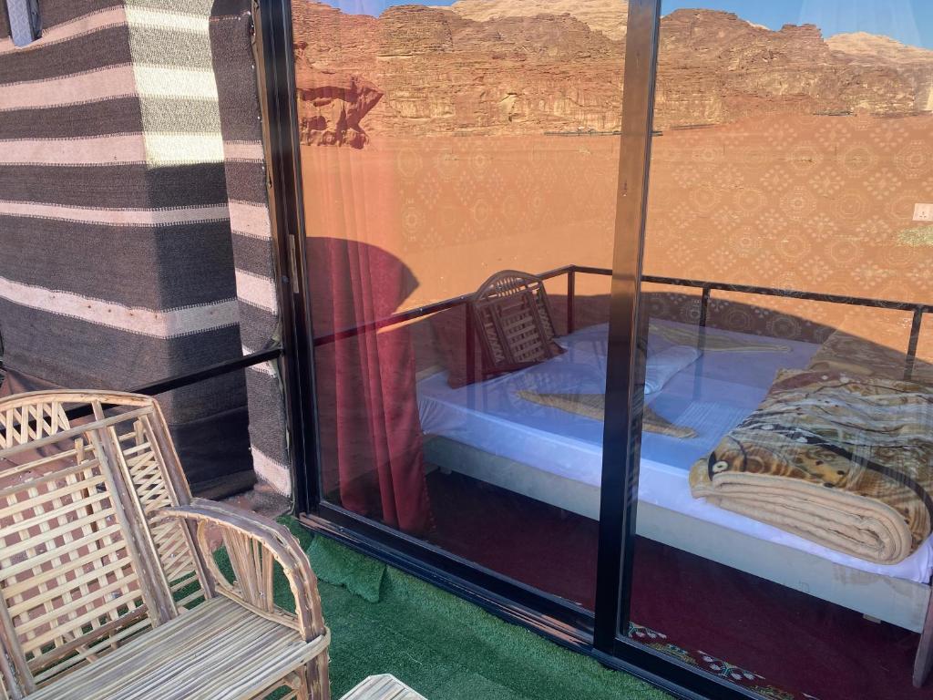 瓦迪拉姆Desert shine camp的带阳台的客房配有一张床和椅子