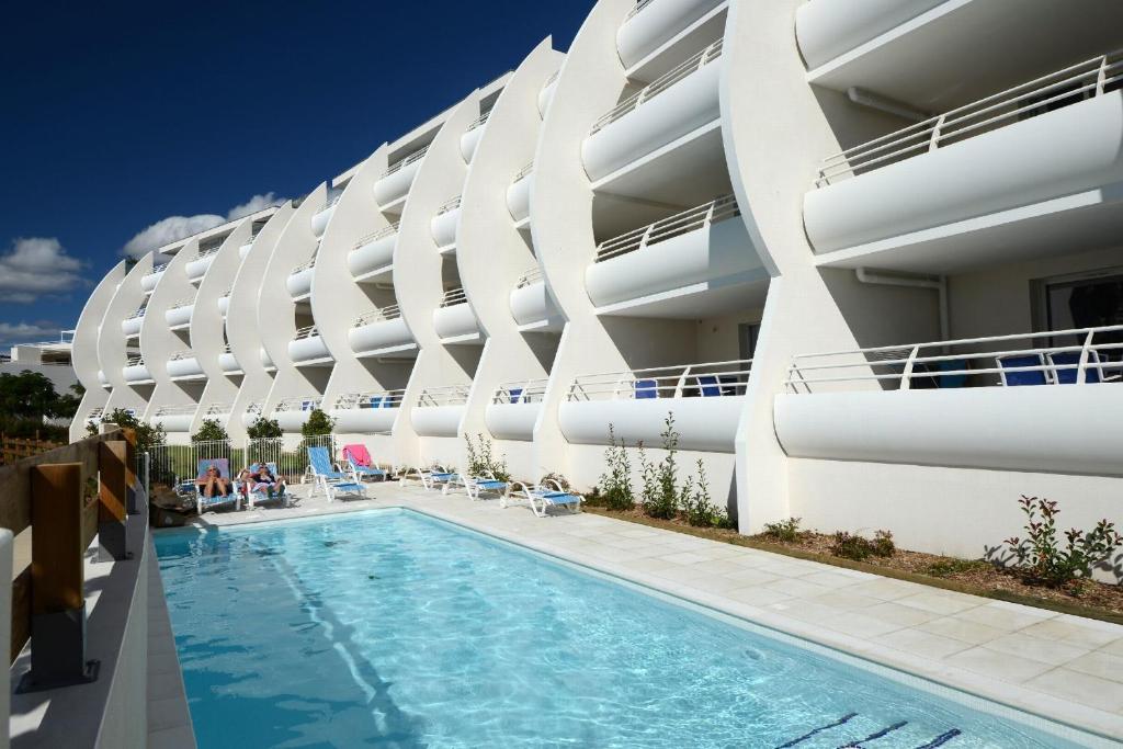拉格朗德默特Résidence Odalys Les Dunes du Soleil的大楼前设有游泳池的酒店