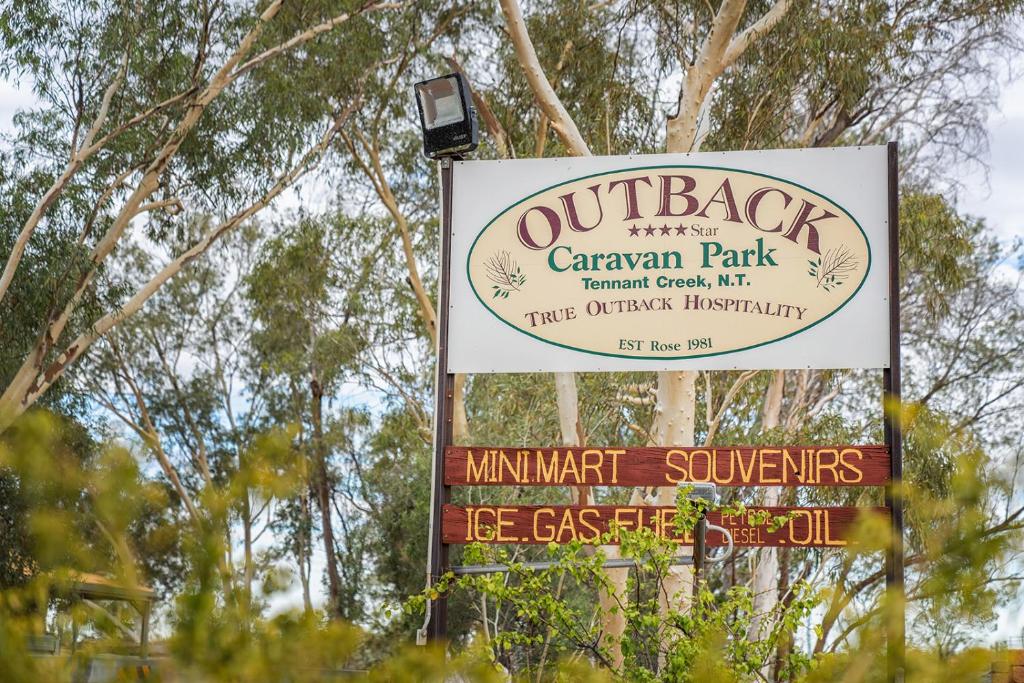 滕南特克里克Outback Caravan Park Tennant Creek的树下公园的标志