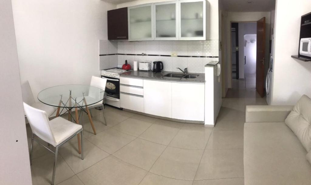 罗萨里奥Loft Espectacular Céntrico con Garaje的厨房配有白色橱柜和玻璃桌