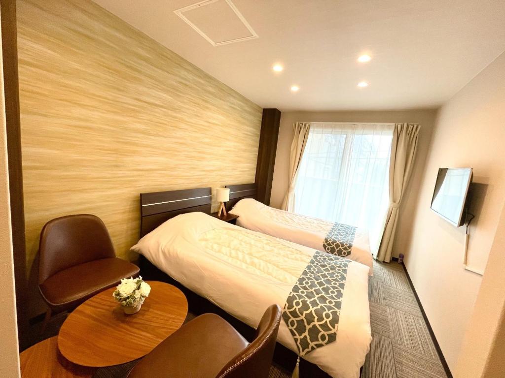 东京winco - Vacation STAY 06648v的酒店客房带两张床和一张桌子以及椅子。