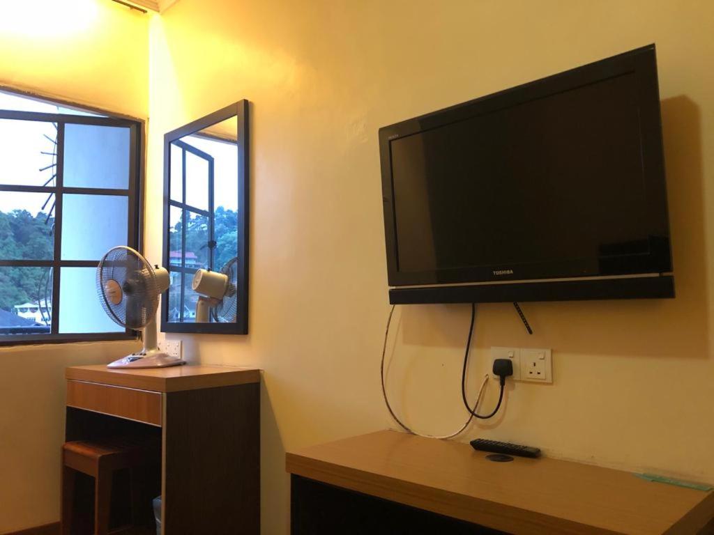 金马仑高原蔡氏杜松子酒酒店的客厅的墙上配有平面电视。