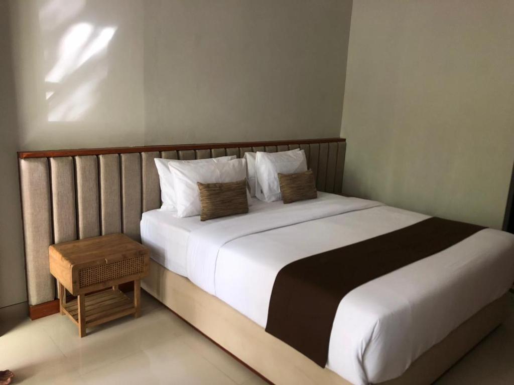 沙努尔德薇德薇别墅酒店的卧室配有一张带白色床单和枕头的大床。
