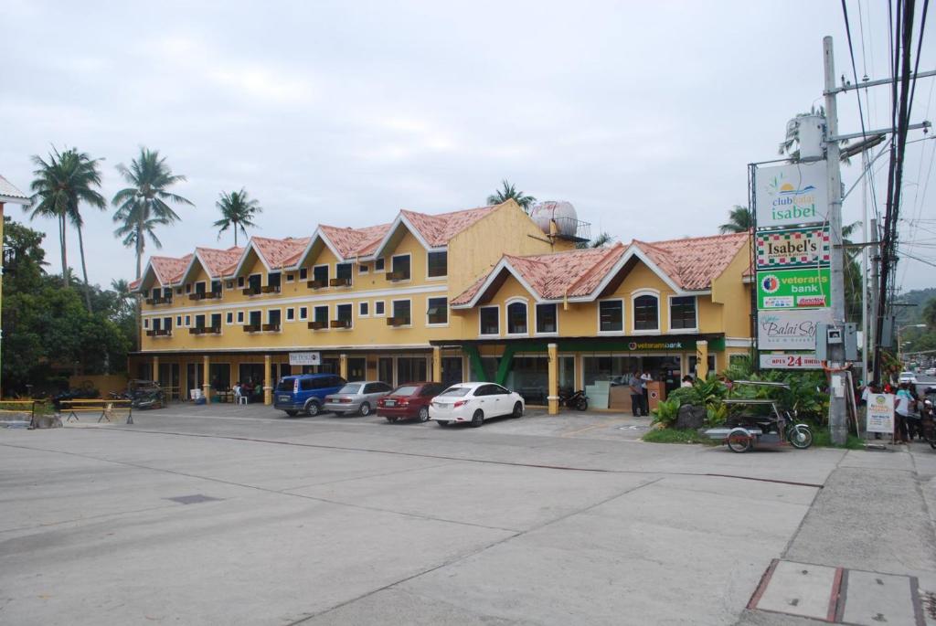 TalisayRedDoorz Plus at Balai Sofia Bed & Breakfast Batangas的停车场内停放汽车的大型建筑