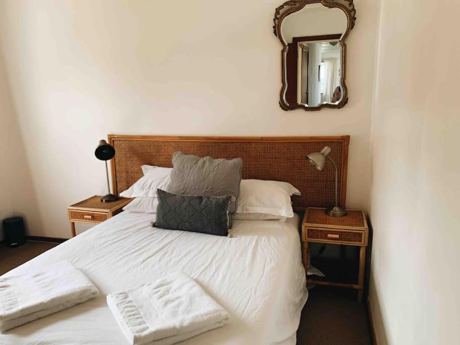 杰弗里湾Sweet & Simple Beach Cottage的卧室配有白色床和墙上的镜子