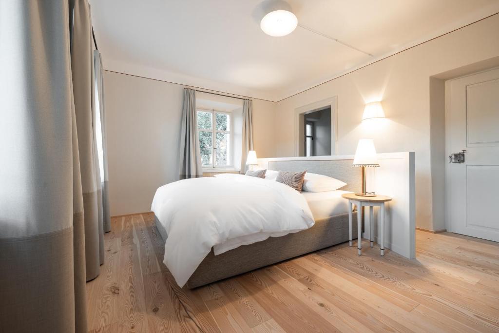 卡尔达罗Smart Suites Kaltern - Apartments am Kalterer See的卧室配有一张白色的大床和一张桌子