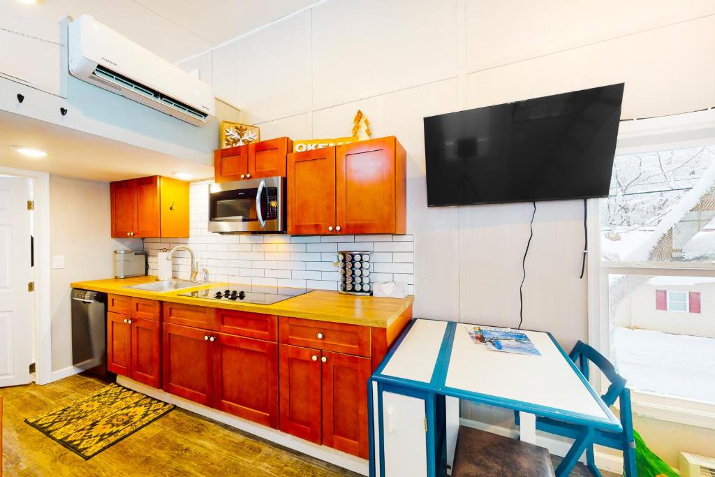 拉德洛Tiny Homes on Pleasant的一间带木制橱柜的厨房和一台墙上的电视