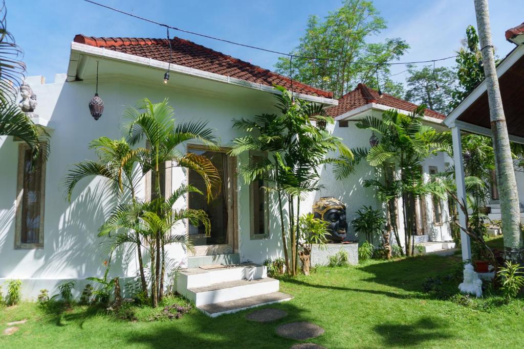 金巴兰Surga Tropical Suites的院子里有棕榈树的白色房子