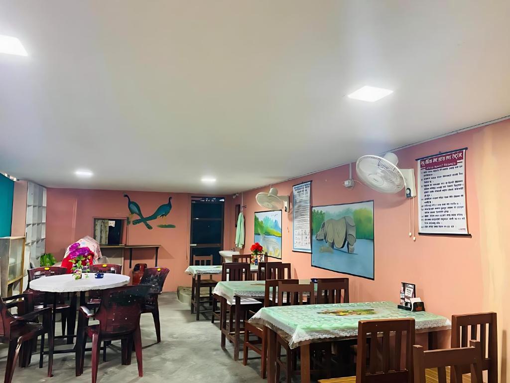 索拉哈Hotel BhupuSainik Sauraha的用餐室配有桌椅和粉红色的墙壁