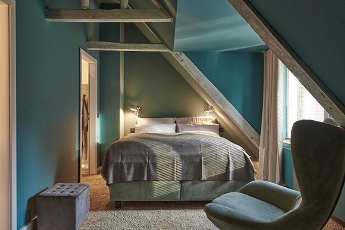 汉堡Landhaus Jenischpark的卧室拥有蓝色的墙壁,配有一张床和椅子