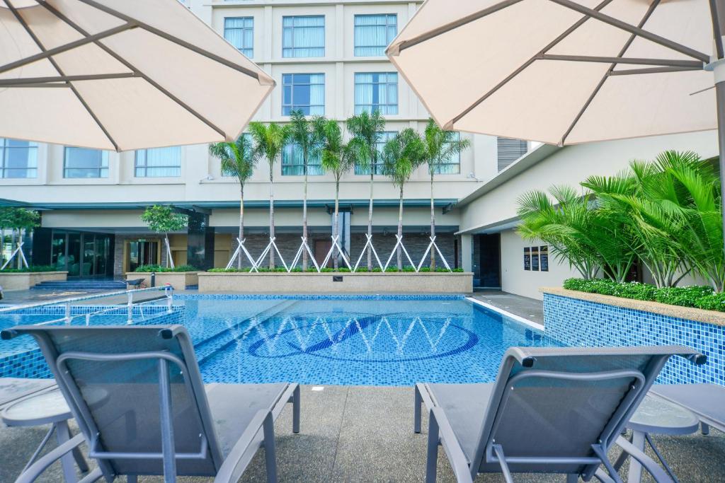 北赖槟城日光酒店的大楼前的游泳池配有椅子和遮阳伞