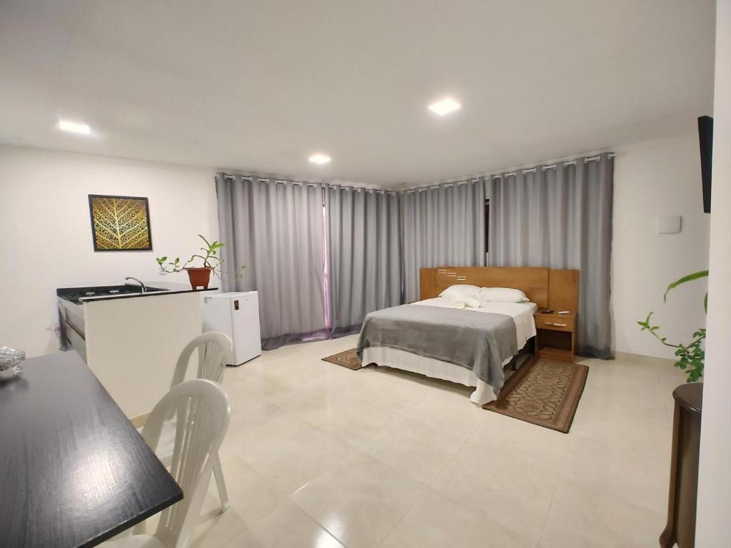 雅帕拉廷加Flats Paraíso Louveny的卧室配有一张床和一张桌子及椅子