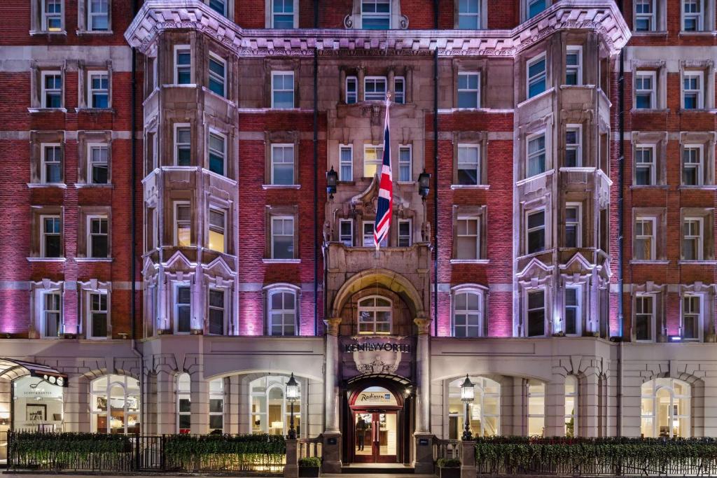 伦敦Radisson Blu Edwardian Kenilworth Hotel, London的前面有旗帜的大砖砌建筑