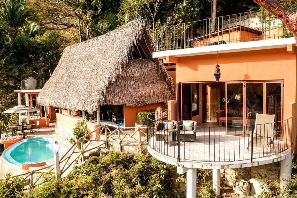 叶莱巴Casa Flourish, Yelapa的茅草屋顶和游泳池的房子