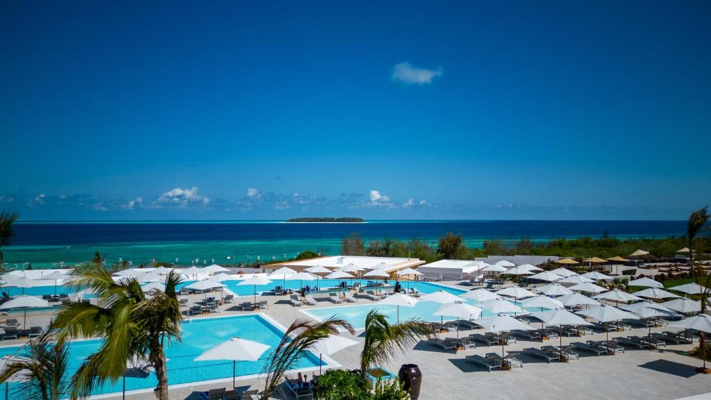 马特姆维The Mora Zanzibar的一个带白色遮阳伞和大海的大型游泳池