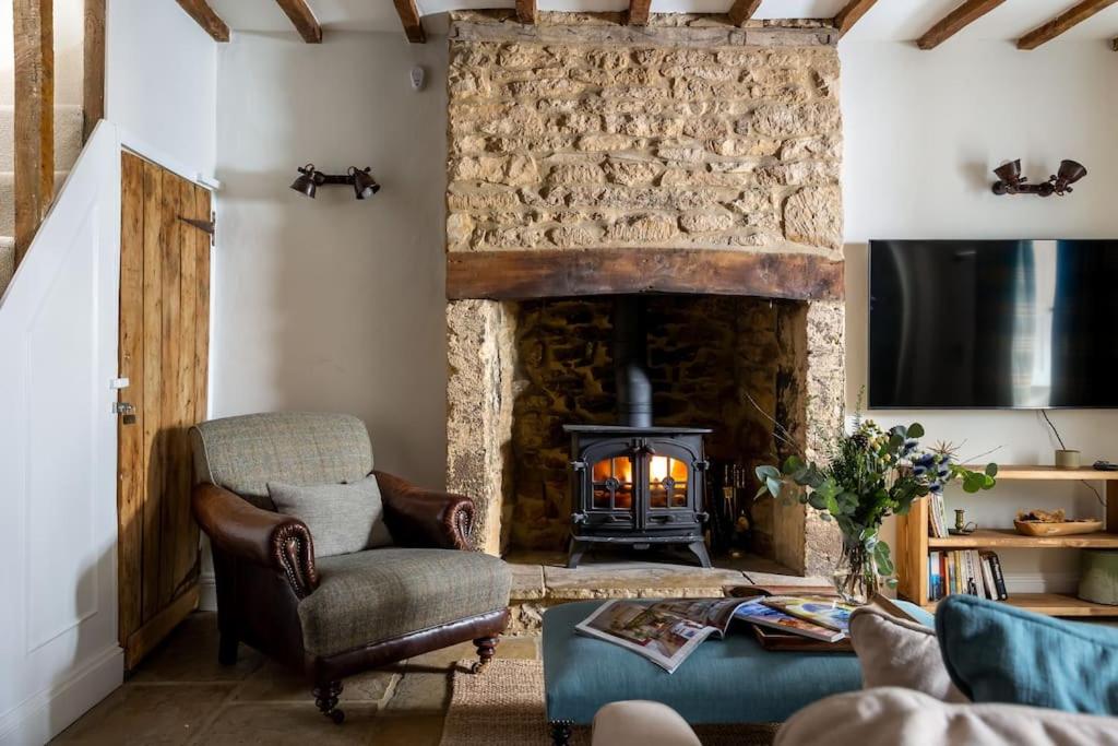 AdlestropCharming 17th Century Cotswold Cottage的客厅设有石制壁炉和椅子