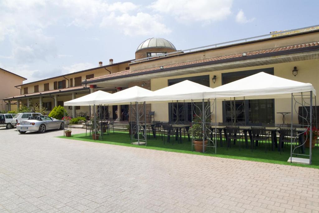 Sigillo多米努丝酒店的前面有桌子和白色遮阳伞的建筑