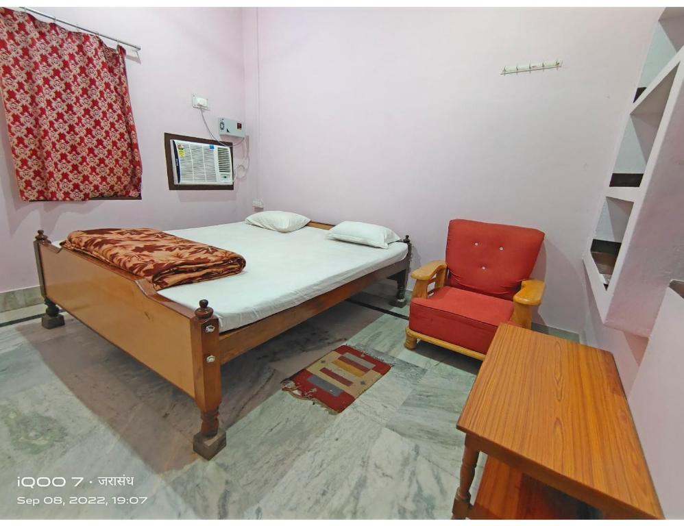SasarāmJarasandh Lodge, Sasaram的一间卧室配有一张床和一张红色椅子